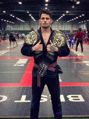 Man poses with two NAGA champion belts