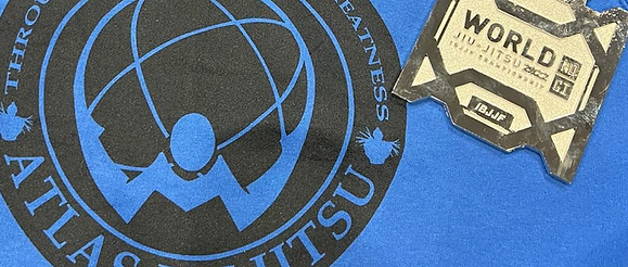 Gold medal on a mat with the Atlas Jiu Jitsu logo