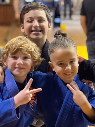 3 children smiling and posing in BJJ gis
